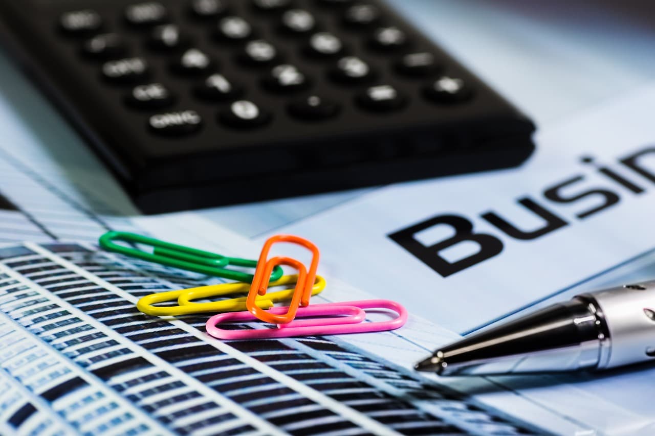 Calculator, papers and paper clips used in organizing expenses for bookkeeping and tax time.