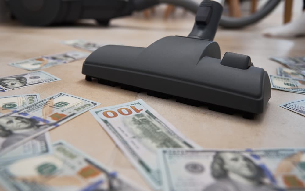 Vacuum clearing 100 dollar bills from floor